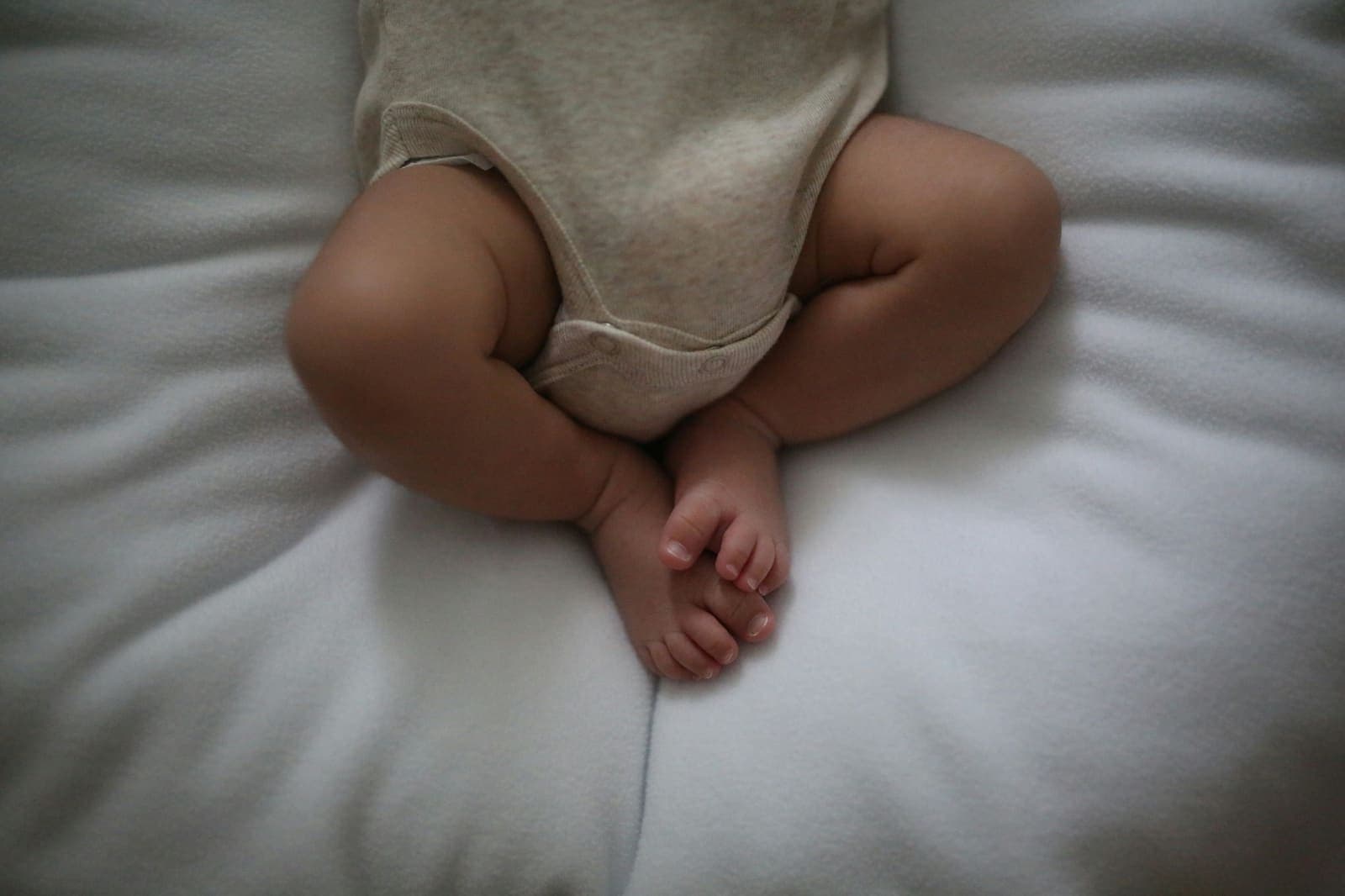 Beine und Füße eines Babys auf einer weißen Decke