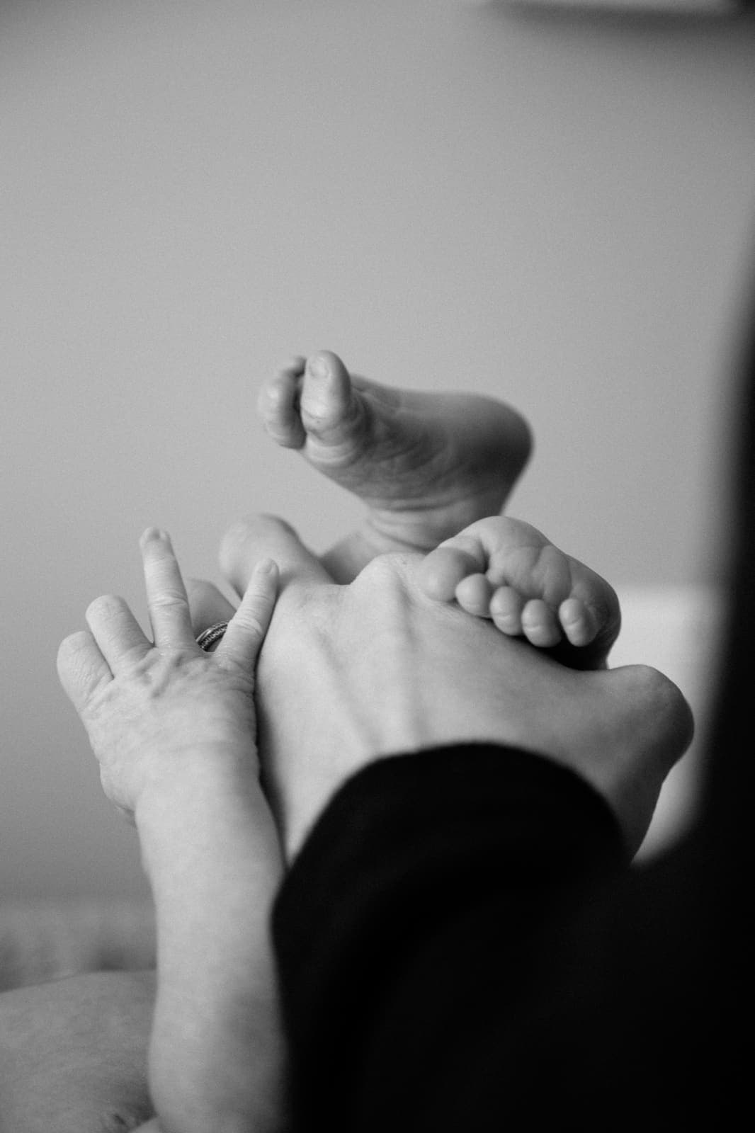 Hand hält die Füße eines Babys (Schwarz-Weiß-Foto)